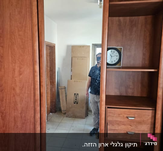 ארון עץ עם מראה ומדפים, קופסאות קרטון ברקע